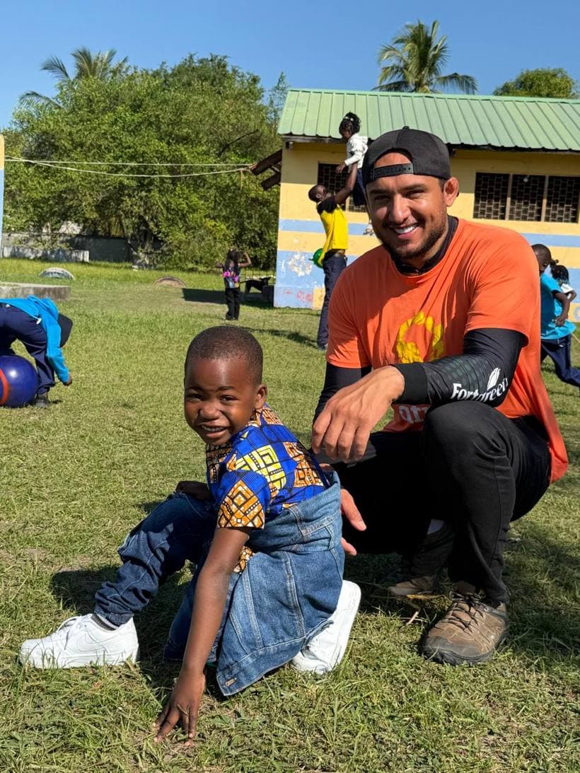 Criança em Moçambique ao lado de um voluntário